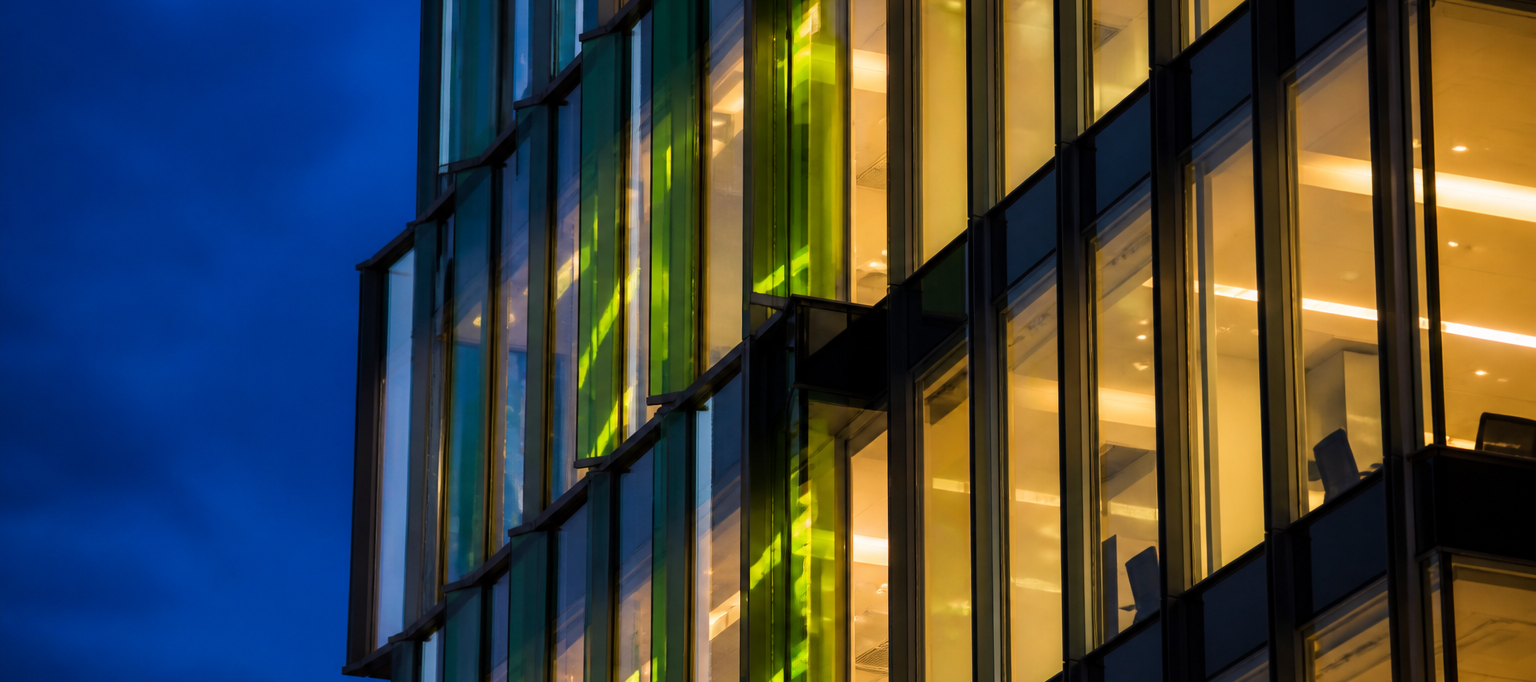 Glass office building at dusk with lit windows
